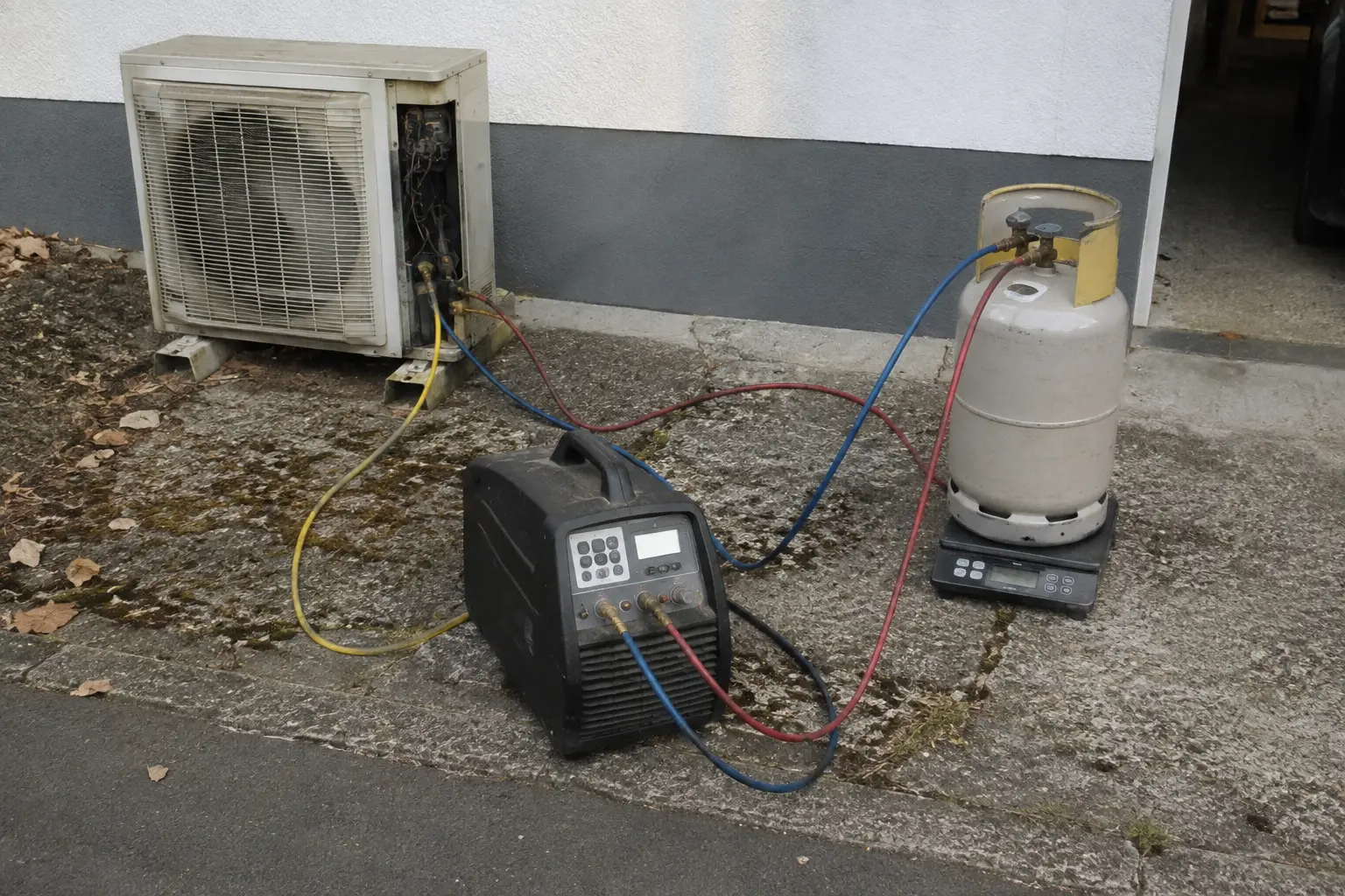 Refrigerant recovery machine and cylinder on a scale during heat pump removal